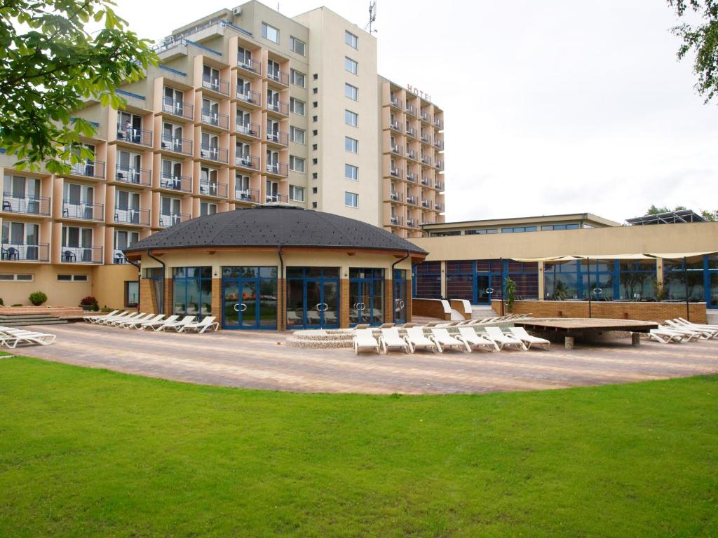 a building with a picnic table and chairs in a park at Premium Hotel Panoráma in Siófok