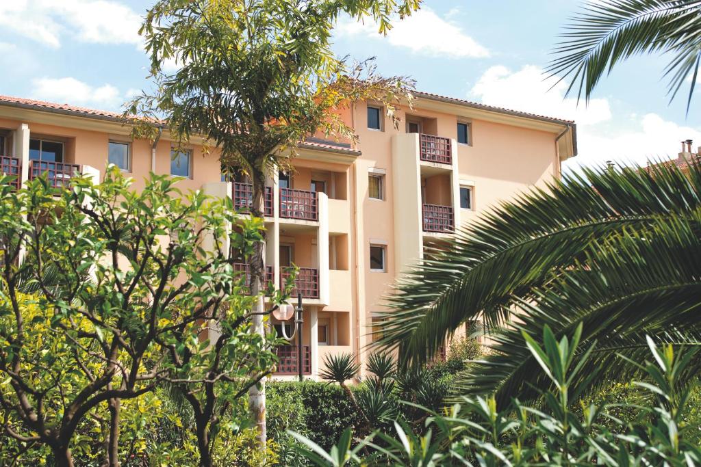 an apartment building with trees in front of it at Résidence Pierre & Vacances Les Citronniers in Menton