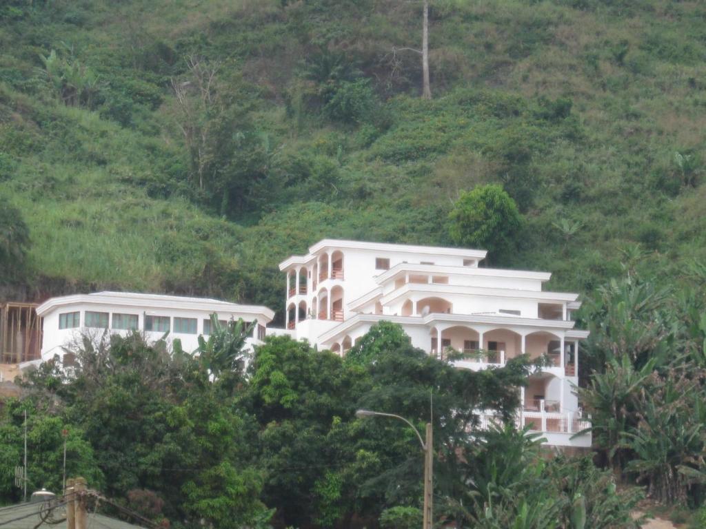 a large white house on a hill with trees at Centre d'Accueil Deo Gratias in Yaoundé