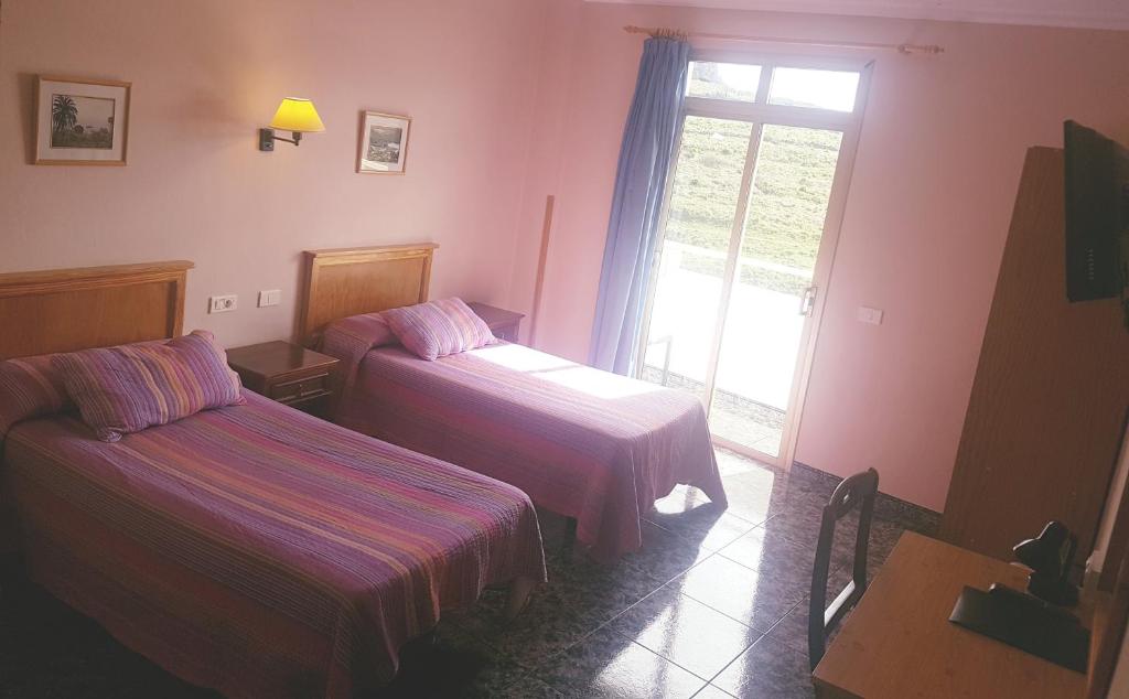 a hotel room with two beds and a window at Hotel Sonia Chipude in El Cercado