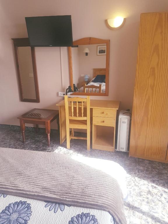 a bedroom with a desk and a bed and a mirror at Hotel Sonia Chipude in El Cercado