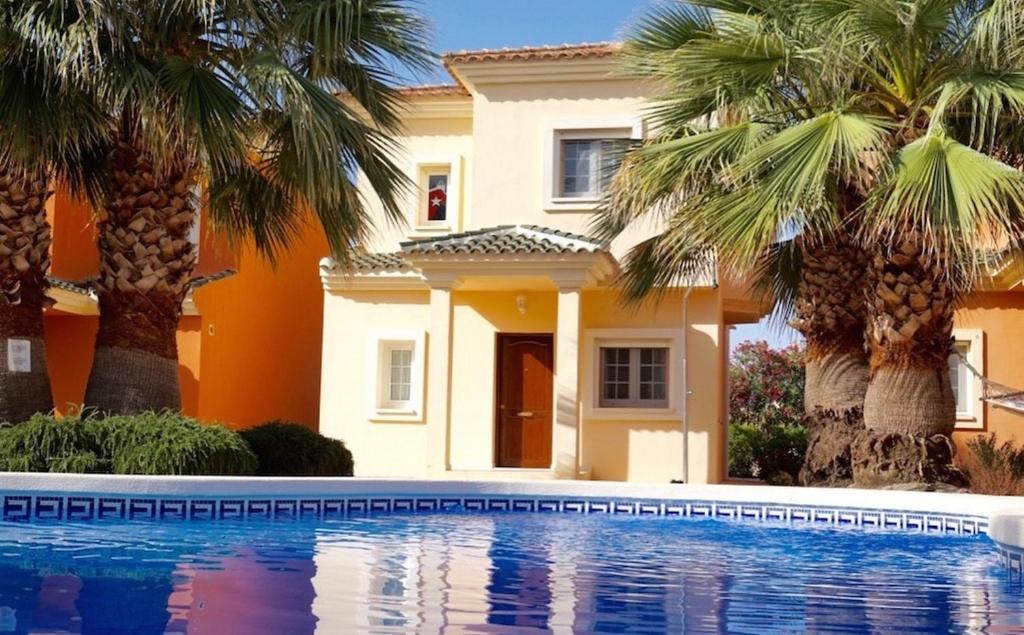 a house with palm trees in front of a swimming pool at Villa Mosa - A Murcia Holiday Rentals Property in Baños y Mendigo