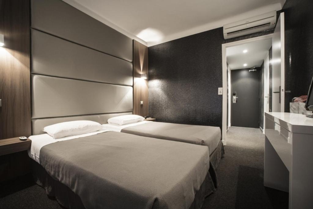 a hotel room with two beds and a sink at Hotel Schtak in Cannes