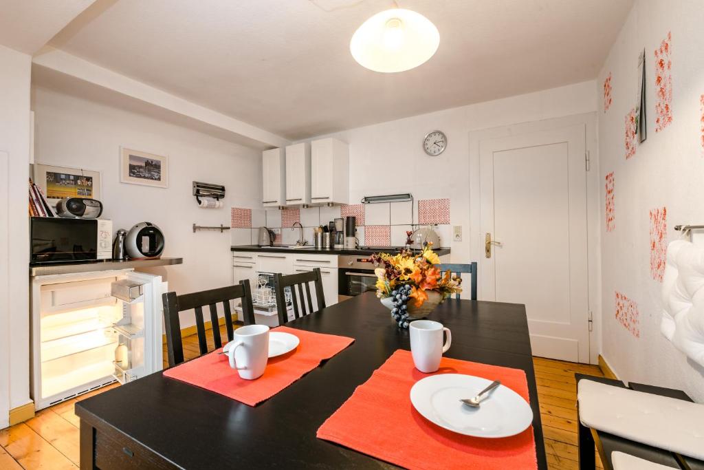 eine Küche und ein Esszimmer mit einem schwarzen Tisch und roten Platzmatten in der Unterkunft Ferienwohnung Alexandra in Heilbad Heiligenstadt