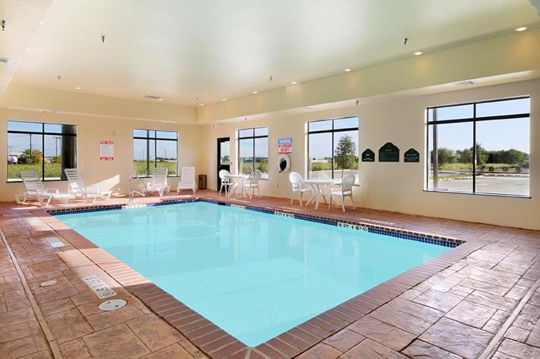 a large swimming pool in a large room with tables and chairs at Wingate by Wyndham New Braunfels in New Braunfels