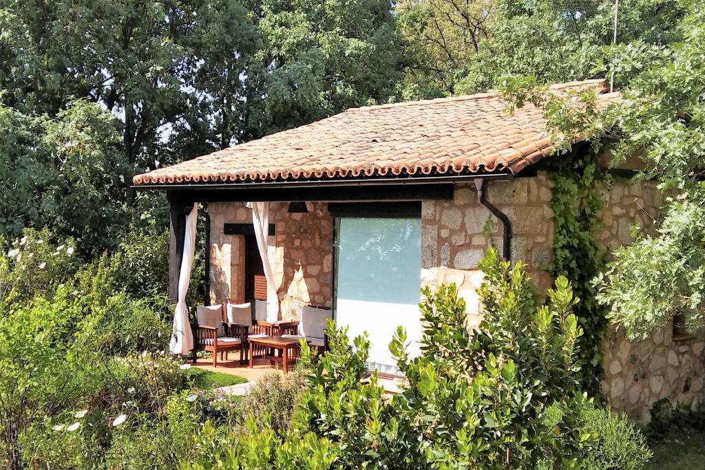 a small stone house with a table and chairs at Apartamentos El Roble in Valverde de la Vera