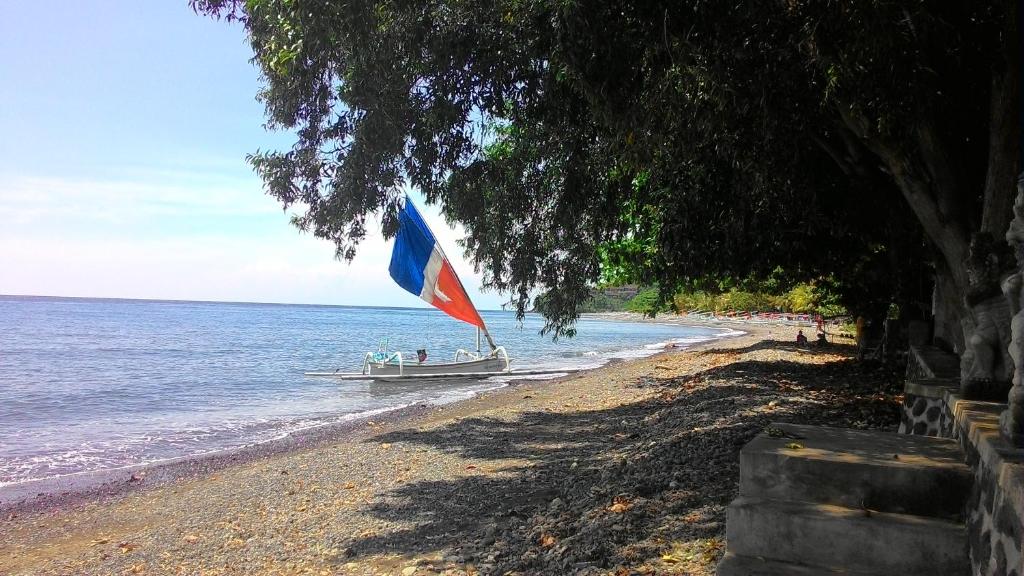 a boat on the beach with a flag on it at Bali Dream House in Amed