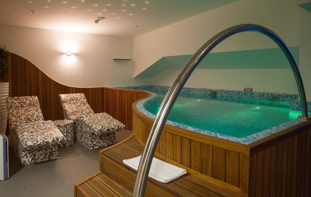 uma banheira de hidromassagem num quarto de hotel com cadeiras em Hotel Aurel em Podgorica