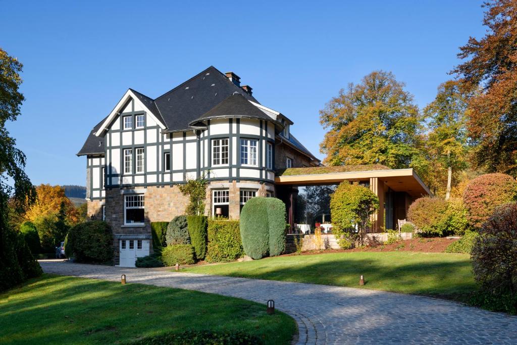 a large black and white house with a driveway at Romantik Hotel le Val d'Amblève in Stavelot