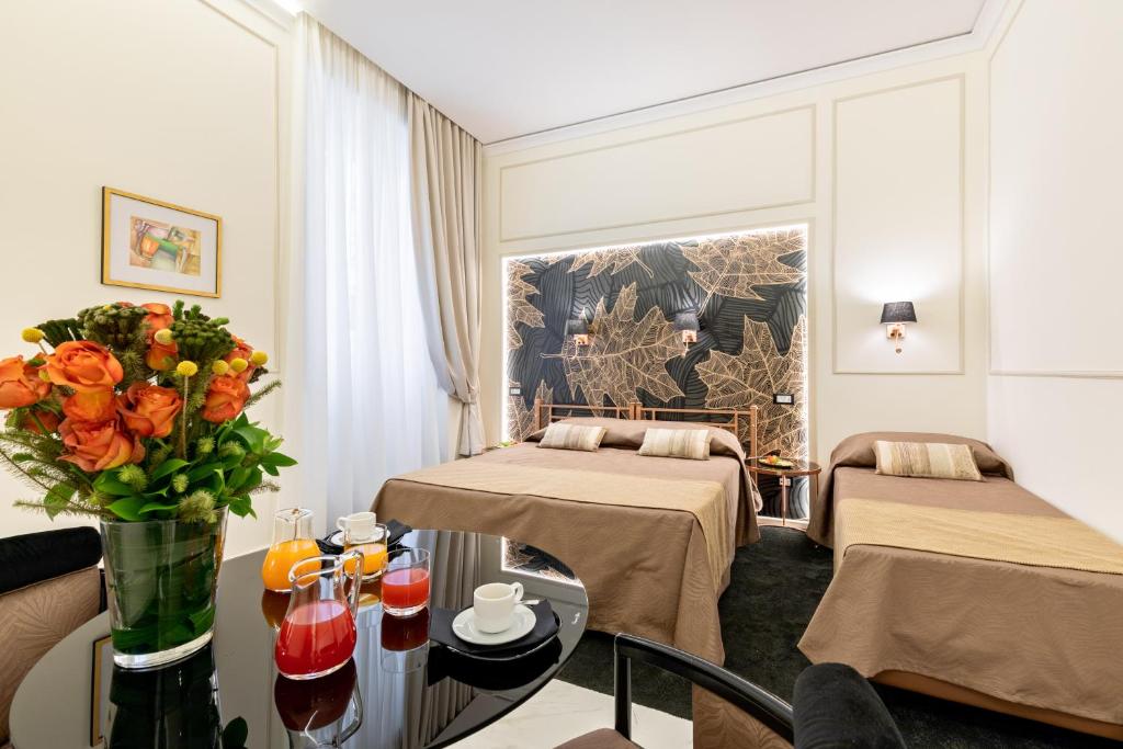 Cavour Suites Guest House في روما: غرفة بسريرين وطاولة بها ورد