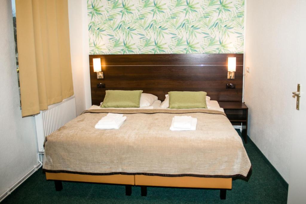 a bedroom with a large bed with a wooden headboard at Hotel Polonia - Frankfurt&#47;Oder in Frankfurt Oder