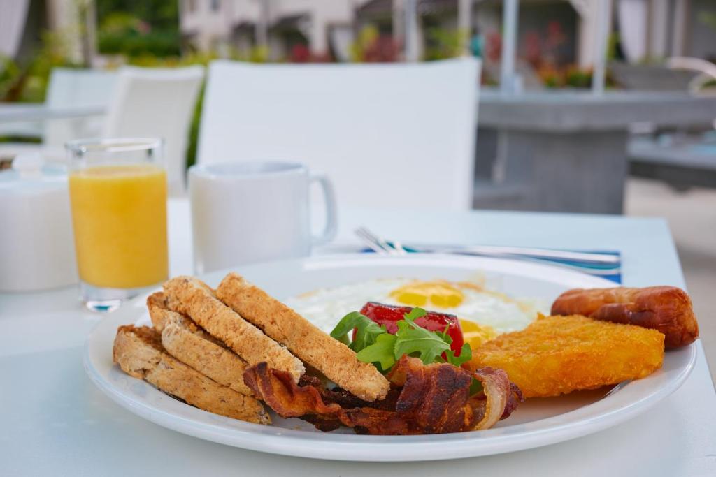 a plate of breakfast food with bacon and eggs and a glass of orange juice at Beach View Hotel in Saint James
