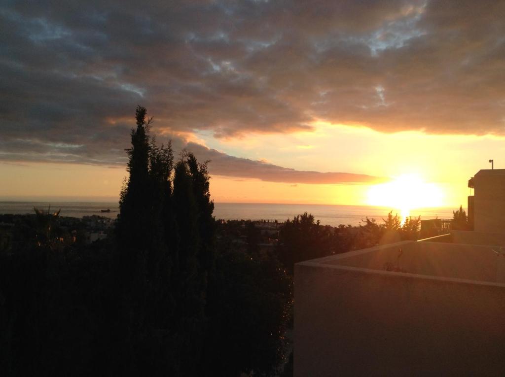 パフォスにあるPelagos Hill Apartmentの建物のバルコニーから見る夕日