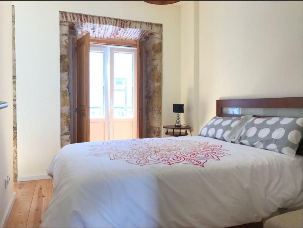 um quarto com uma grande cama branca e uma janela em Central Madragoa Flat em Lisboa