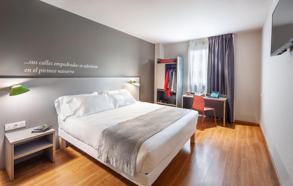 Un dormitorio con una cama grande y un escritorio. en ibis Styles Pamplona Noain, en Noáin