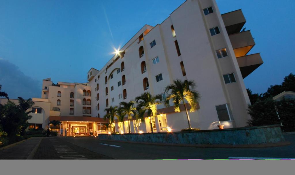 African Regent Hotel في آكرا: مبنى كبير أمامه أشجار نخيل