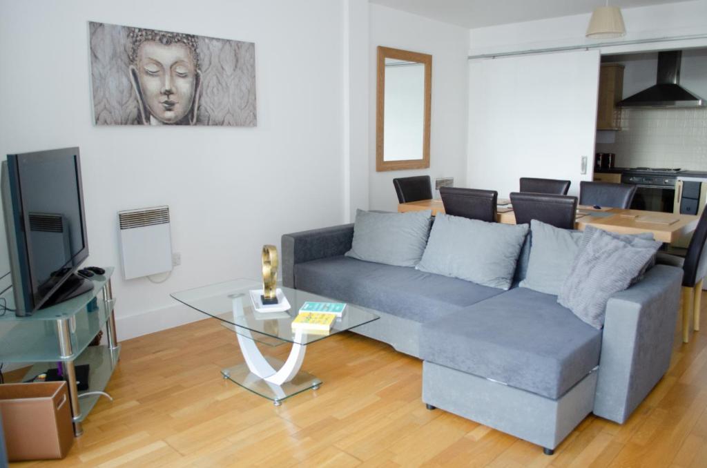 a living room with a blue couch and a television at Serviced Apartment In Liverpool City Centre - Free Parking - Balcony - by Happy Days in Liverpool