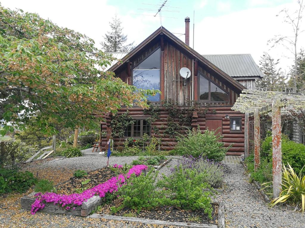 a log cabin with purple flowers in front of it at Ruapehu Log Lodge in Raetihi