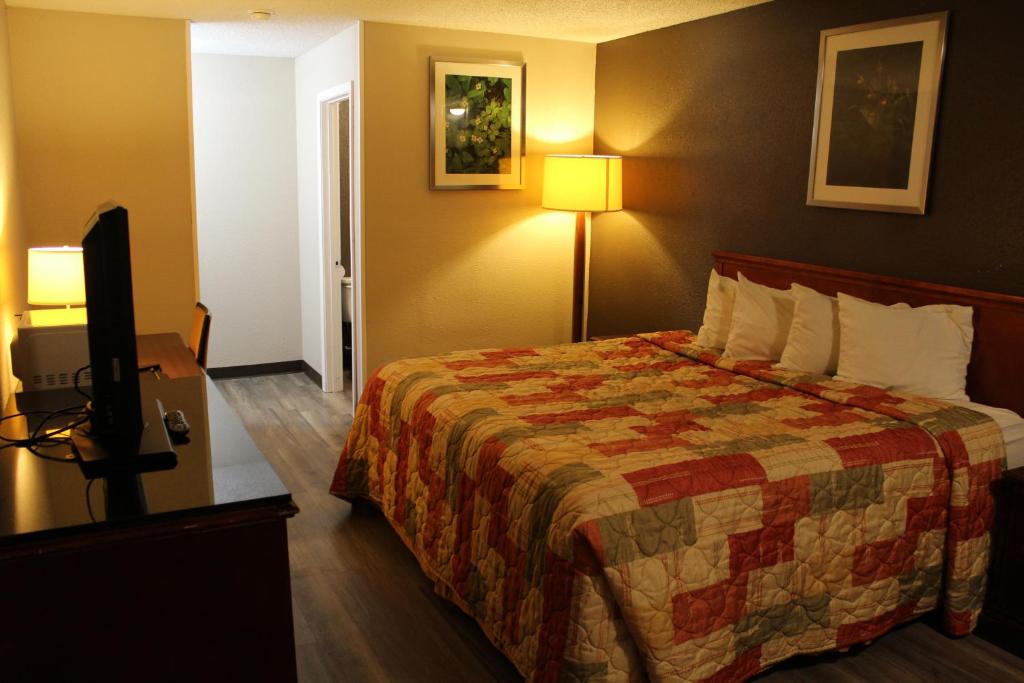 a hotel room with a bed and a flat screen tv at Regency Inn in Rolla