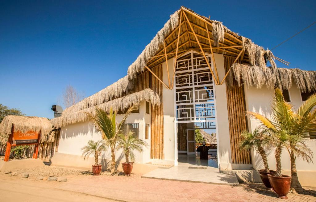 un bâtiment avec des palmiers en face de celui-ci dans l'établissement Vichayito Bungalows & Carpas, à Vichayito