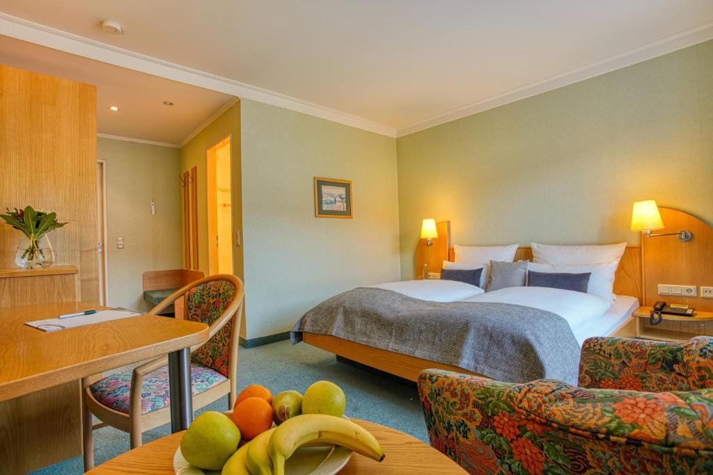 a hotel room with two beds and fruit on a table at Hotel Kischers Landhaus in Hannover