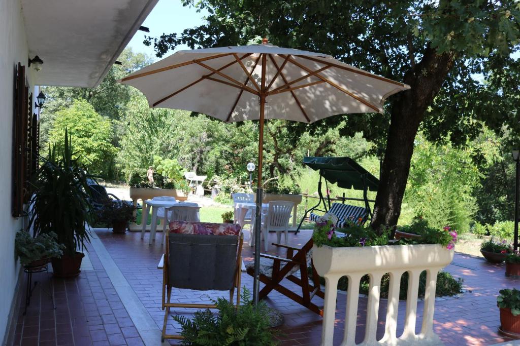 eine Terrasse mit Tischen, Stühlen und einem Sonnenschirm in der Unterkunft Boscodisotto in Rapolano Terme