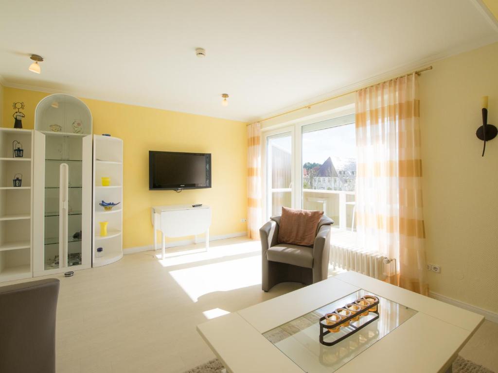 ein Wohnzimmer mit einem TV, einem Stuhl und einem Tisch in der Unterkunft Haus Regina in Timmendorfer Strand