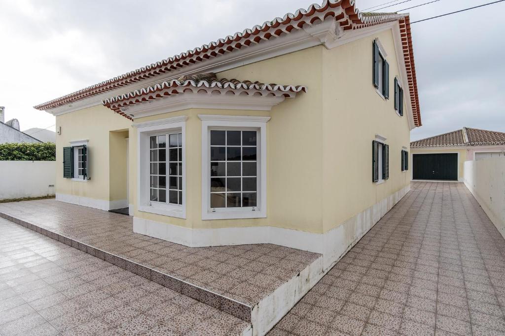 a large white house with a tile driveway at Casa dos Amigos in Ribeira Grande