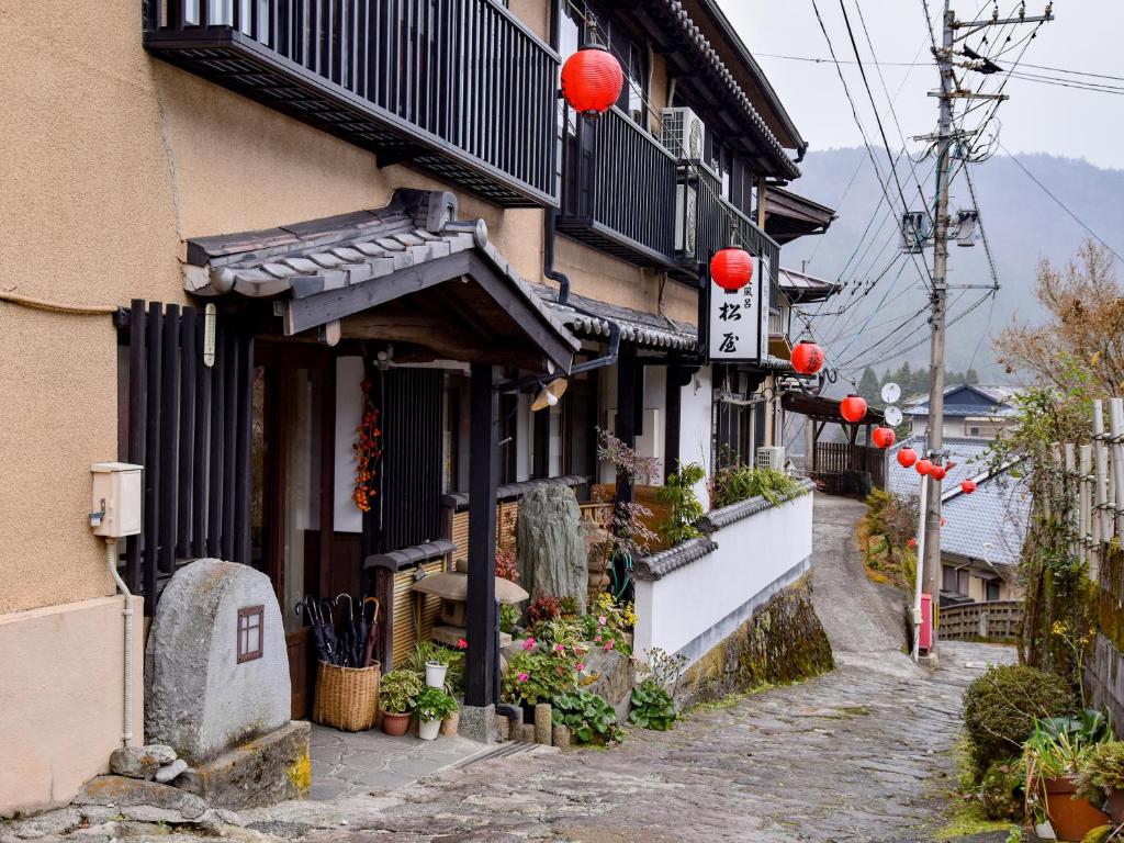 湯布院的住宿－Sanso Matsuya，街道边有红色灯笼的建筑