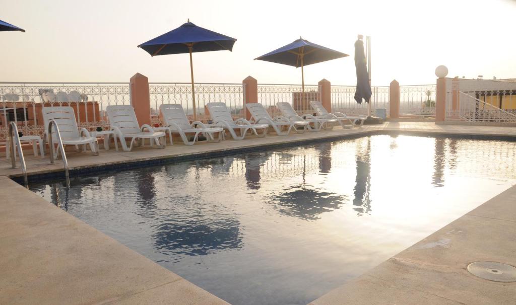 馬拉喀什的住宿－拉辛酒店，一个带躺椅和遮阳伞的游泳池