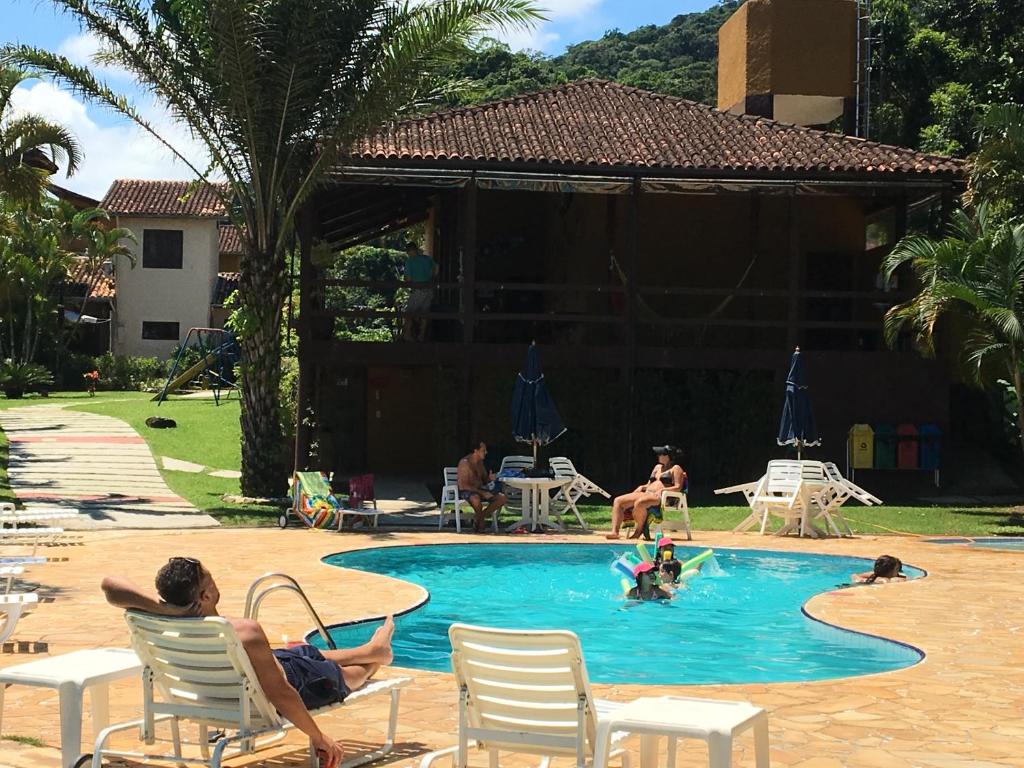 a group of people sitting in chairs in a swimming pool at Chalé Boiçucanga / Maresias in Boicucanga