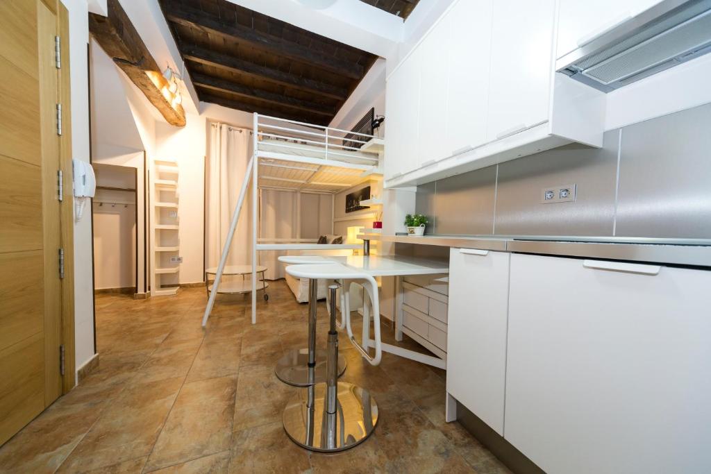 una cucina con mobili bianchi e un tavolo di Apartamento céntrico a 10 minutos de la Alhambra a Granada
