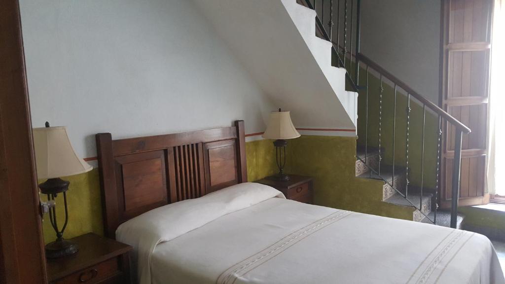 a bedroom with a bed and two lamps and a staircase at Hotel Posada San Jerónimo in Coatepec