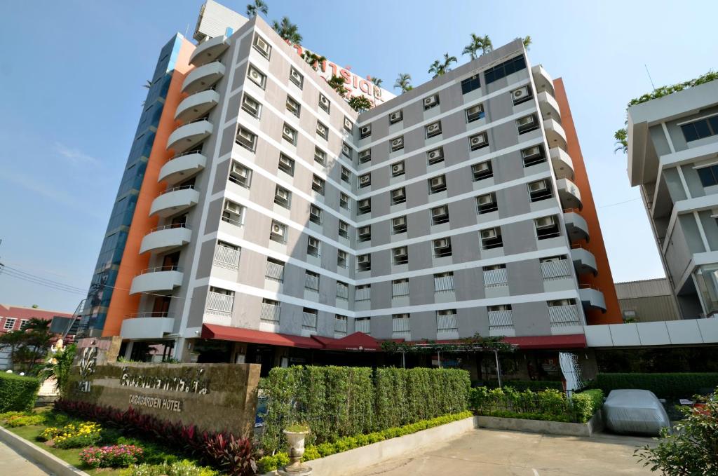 zwei hohe Gebäude mit Büschen vor ihnen in der Unterkunft Tara Garden Hotel in Bangkok