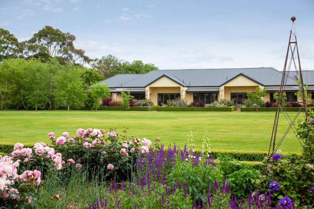 a house with a garden with flowers in the foreground at The Barn Accommodation in Mount Gambier