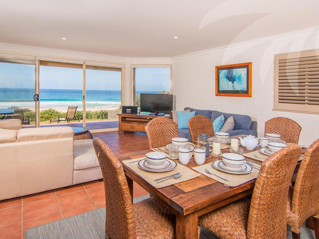 a living room with a table with chairs and a couch at Allure on Blueys in Blueys Beach