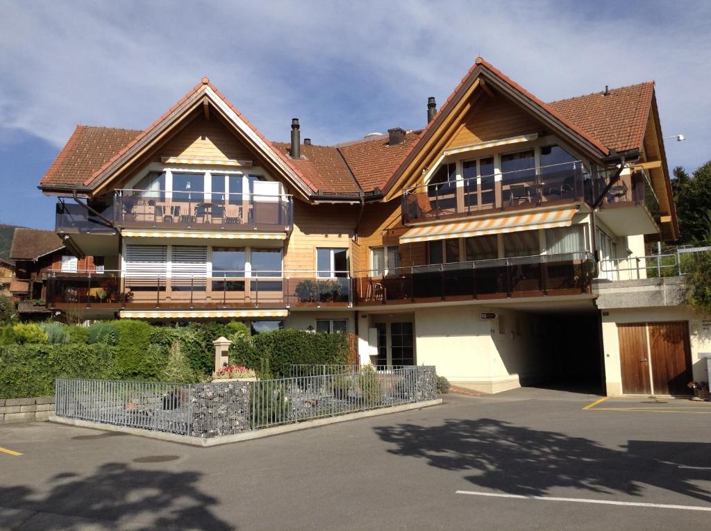 a large wooden house with a parking lot at Lake View Apartment in Faulensee
