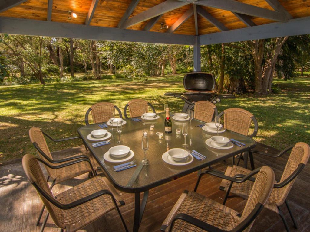 a table with chairs and a grill on a patio at Boomerang Hideaway - at Tranquil acreage in Blueys Beach