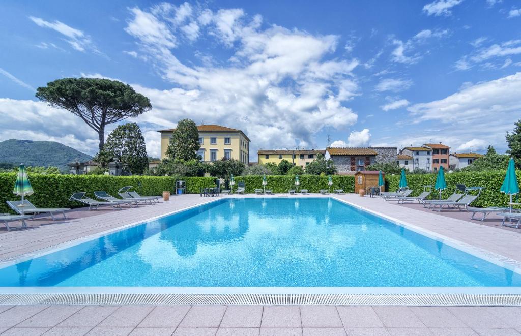 ルッカにあるB&B Villa Pardi Luccaの背景に建つ建物、椅子付きのスイミングプール