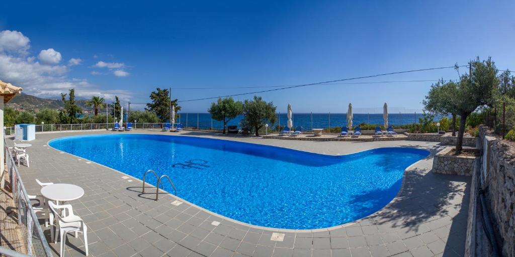 a large blue swimming pool with a view of the ocean at Kardamili Beach Hotel in Kardamili