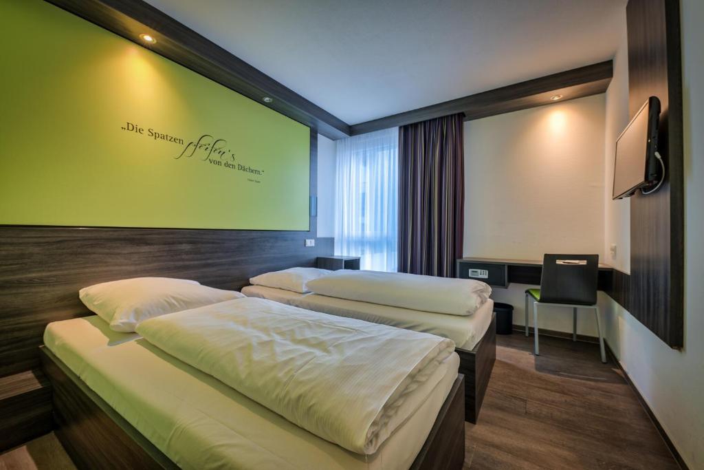 2 Betten in einem Zimmer mit grüner Wand in der Unterkunft Economy-Hotel in Ulm