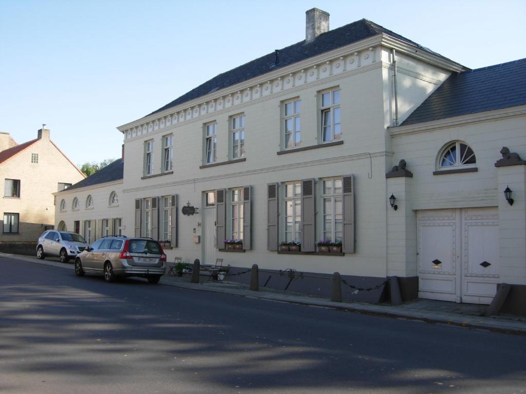 un edificio bianco con macchine parcheggiate di fronte di Landhuis Vedastus a Reningelst