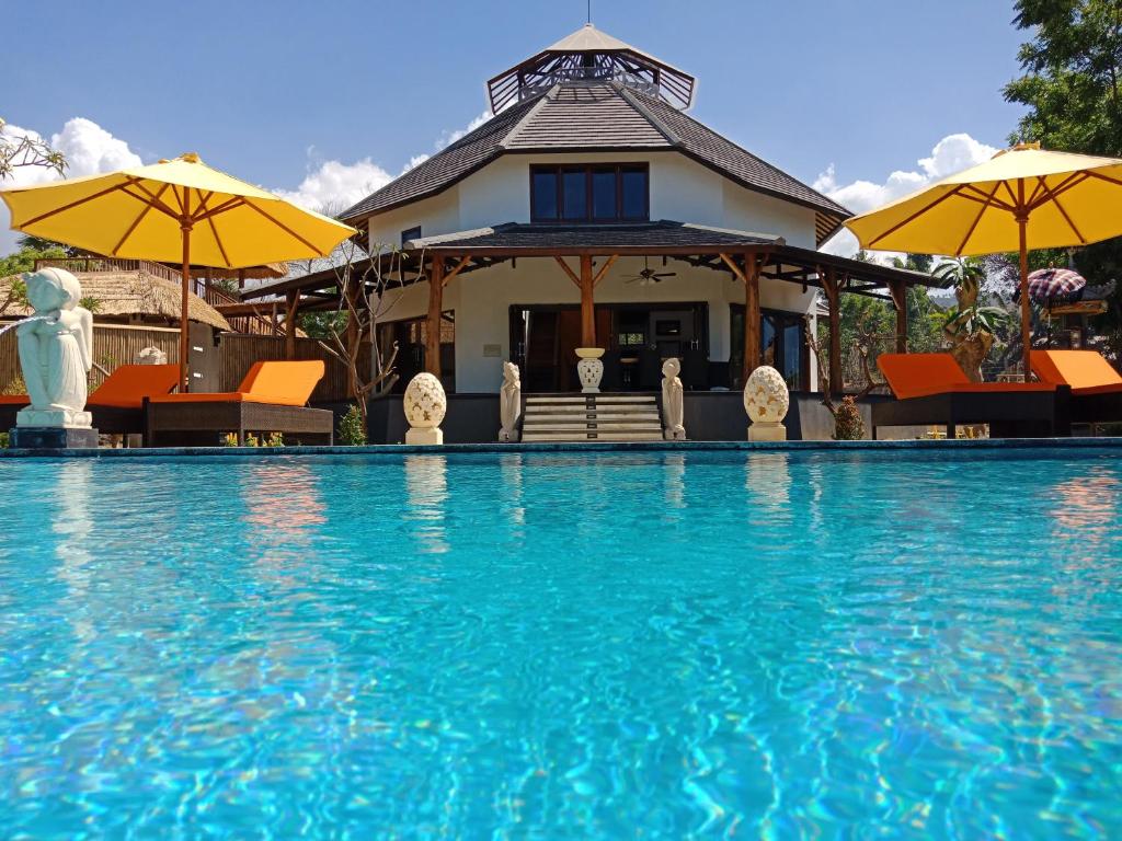 a house with a swimming pool with chairs and umbrellas at Samari Hill Villa in Buleleng