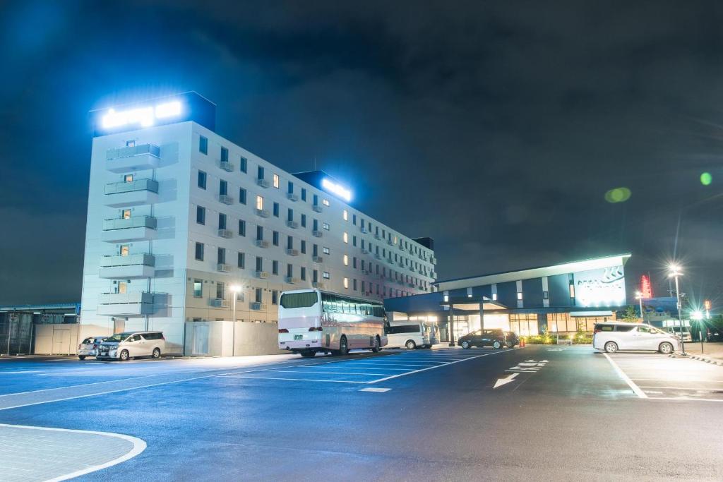 um edifício com carros estacionados num parque de estacionamento à noite em Dormy Inn EXPRESS Sendai Seaside em Sendai