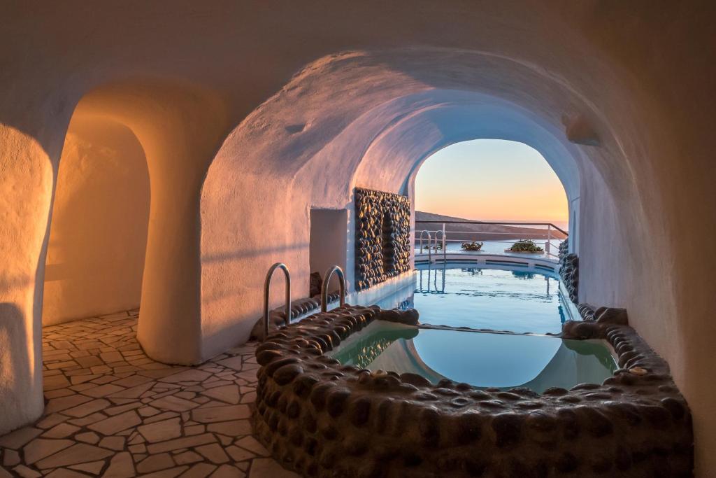 a swimming pool in a house with an arched doorway at Fanari Villas in Oia