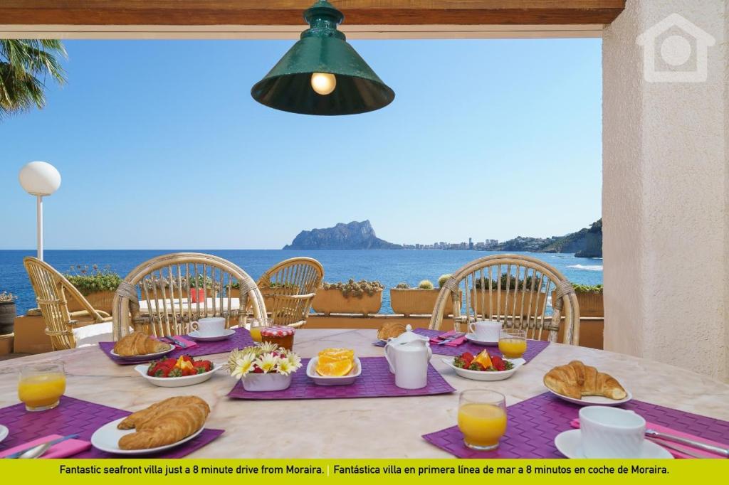 a table with food and a view of the ocean at SolHabitat Villa Papavents in Benissa
