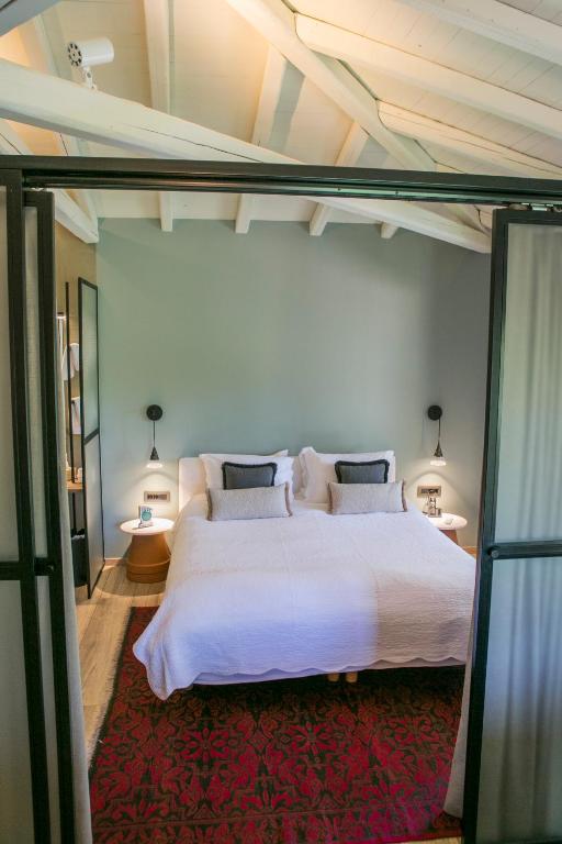 a bedroom with a large white bed and two lamps at Ekies All Senses Resort, a Member of Design Hotels in Vourvourou