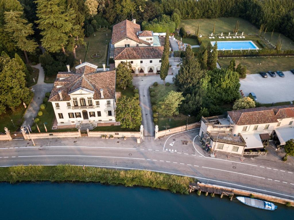 eine Luftansicht eines Hauses mit Straße und Wasser in der Unterkunft Relais et Châteaux Hotel Villa Franceschi in Mira