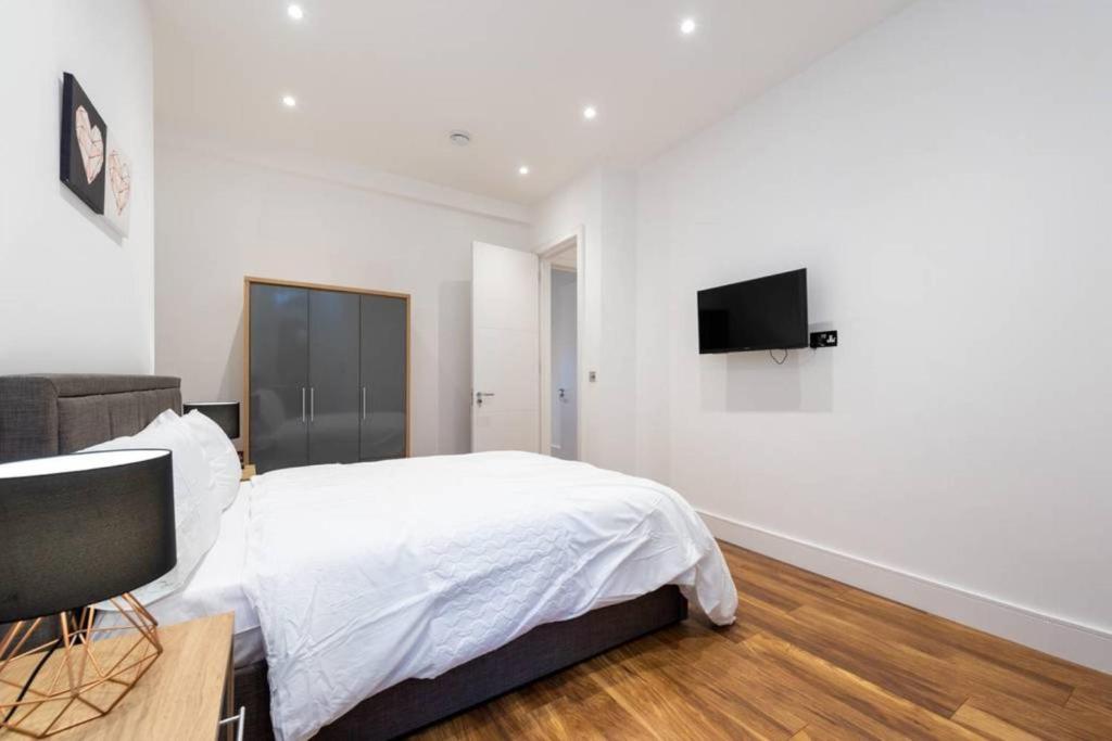 um quarto com uma cama e uma televisão na parede em Spacious and Luxurious London Apartment (MHB352) em Londres