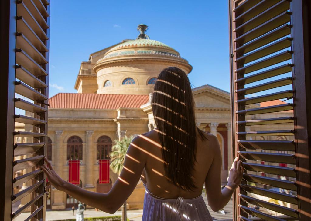 a woman looking out a window at a building at Palazzo Sovrana in Palermo